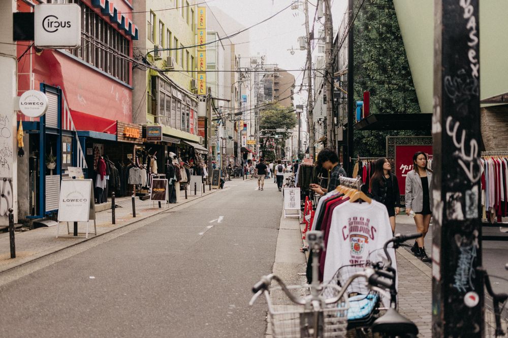 Narrow street lined with shops and businesses in a Japanese urban neighborhood.