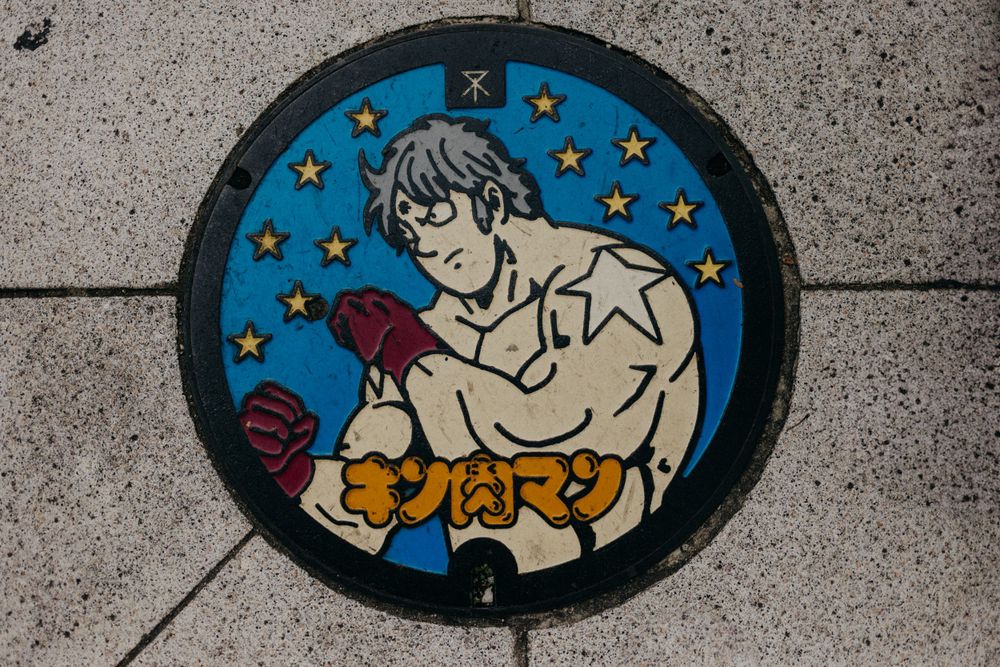 Decorative manhole cover featuring an anime character design on a starry blue background.
