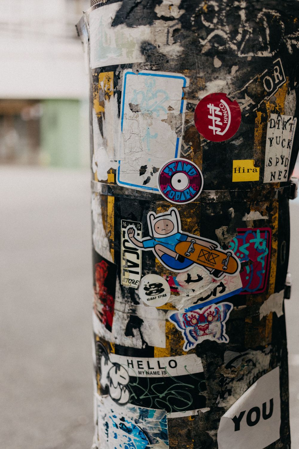 A pole covered in colorful stickers and street art featuring cartoon characters and various designs.