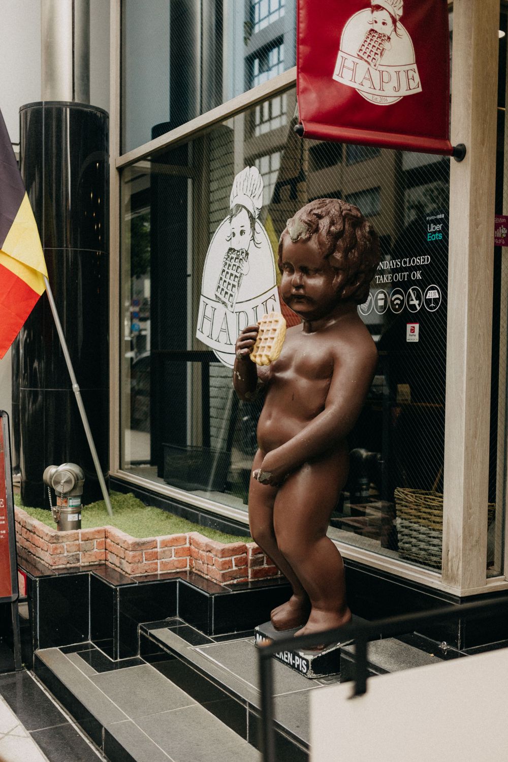 A decorative cherub statue outside a storefront holding a sign.