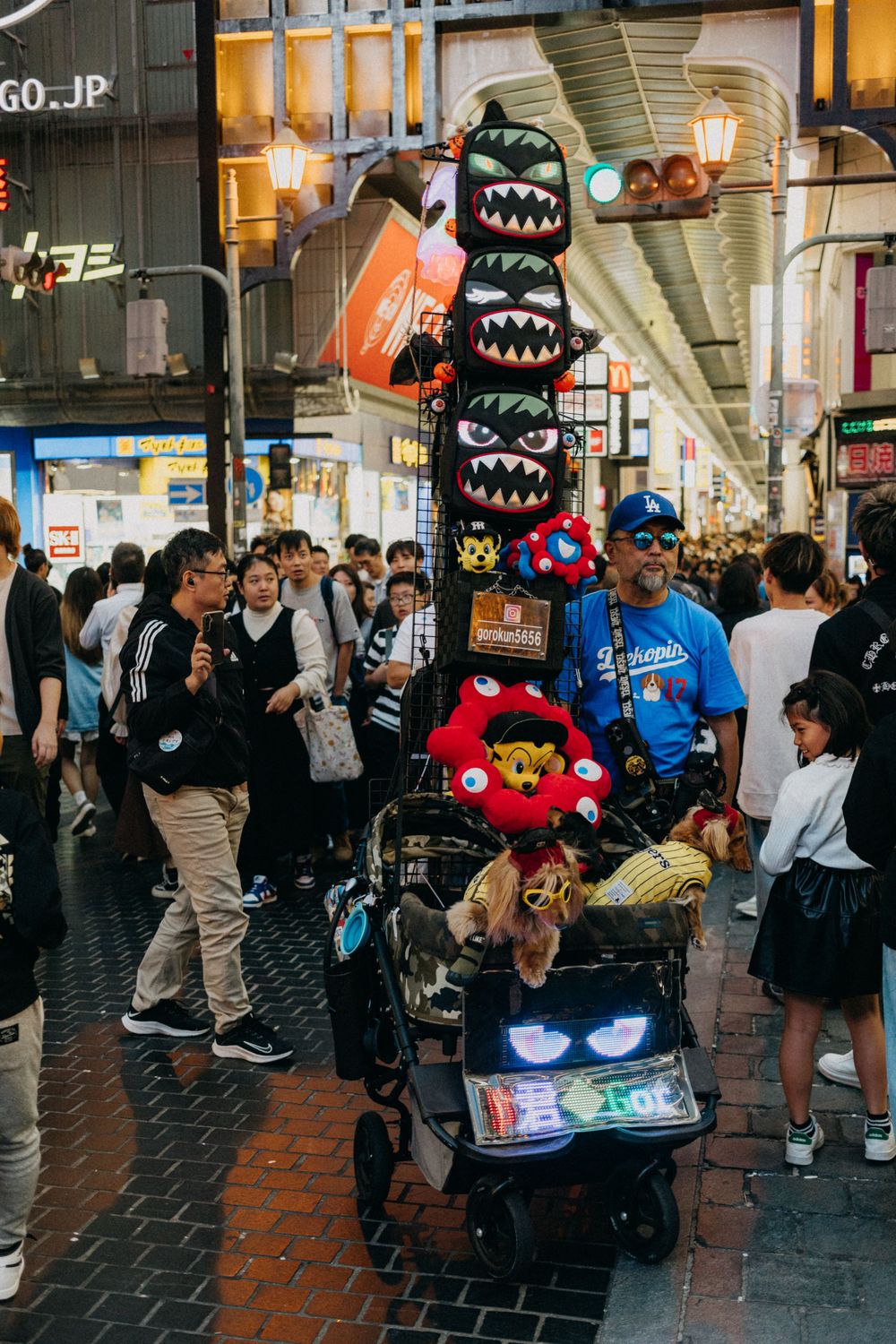 Busy shopping arcade in Japan with vendors selling plush toys and monster-themed merchandise.