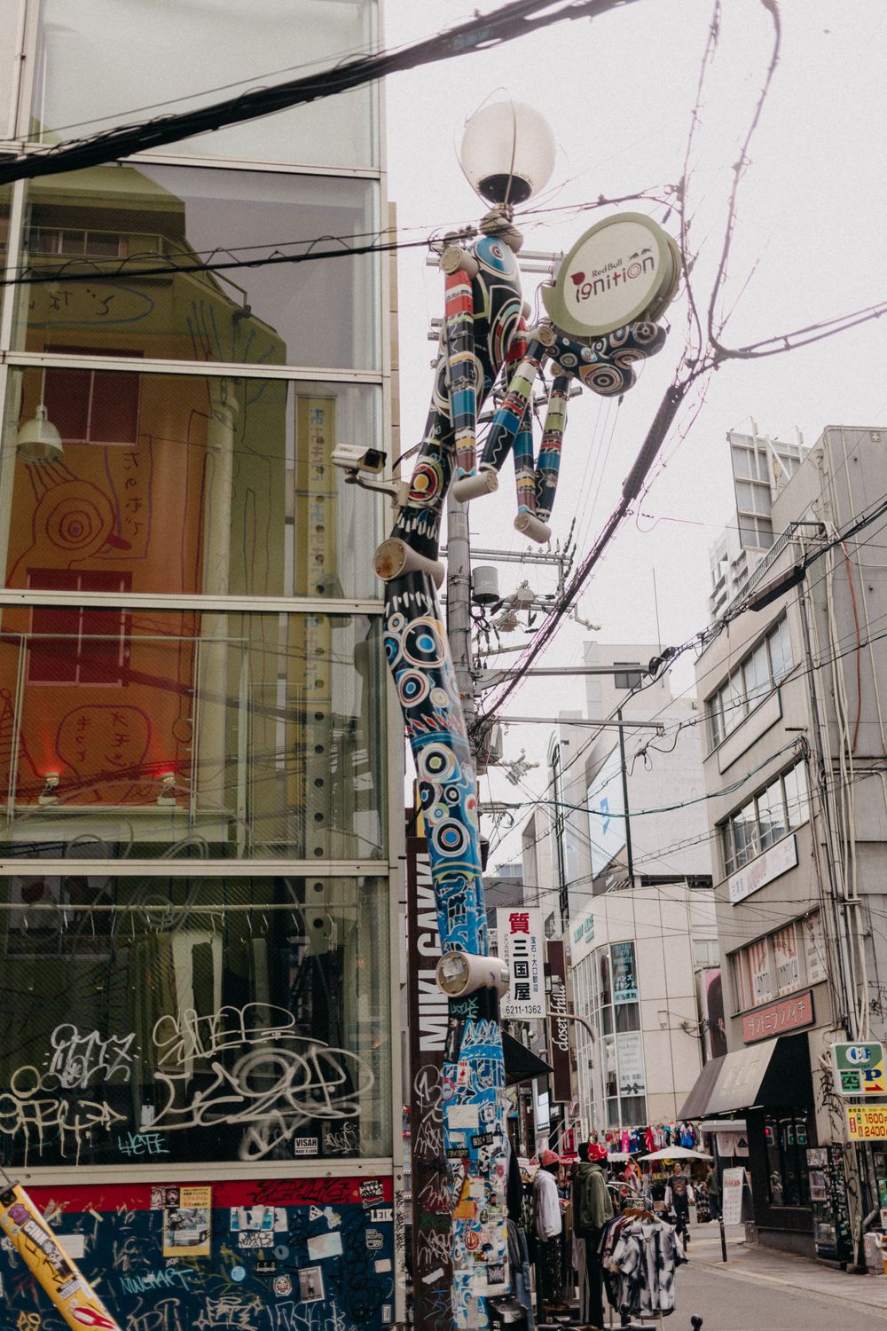 Utility pole covered in stickers and posters on a commercial street in Japan.