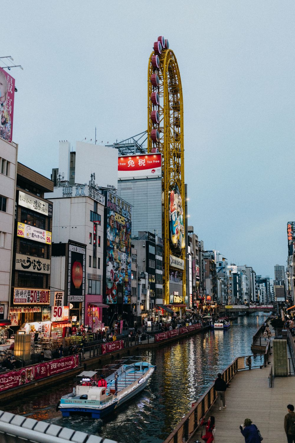 Iconic Dotonbori district in Osaka with tall buildings and a large ferris wheel visible against the sky.