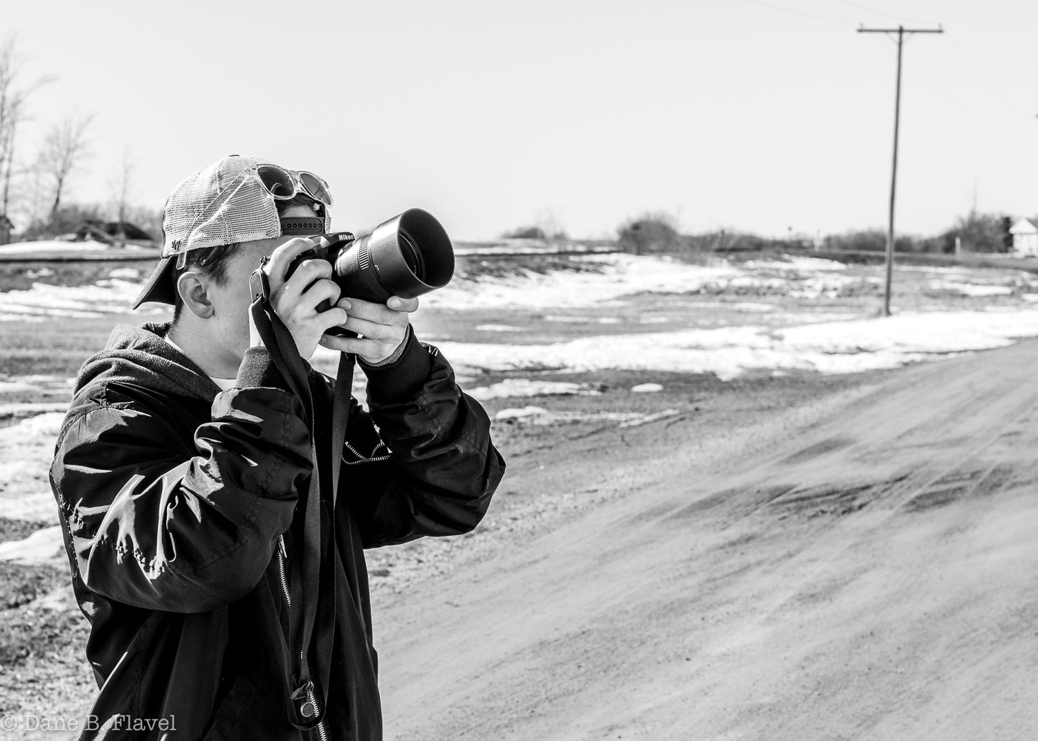 Photographer using telephoto lens to capture images in winter landscape.