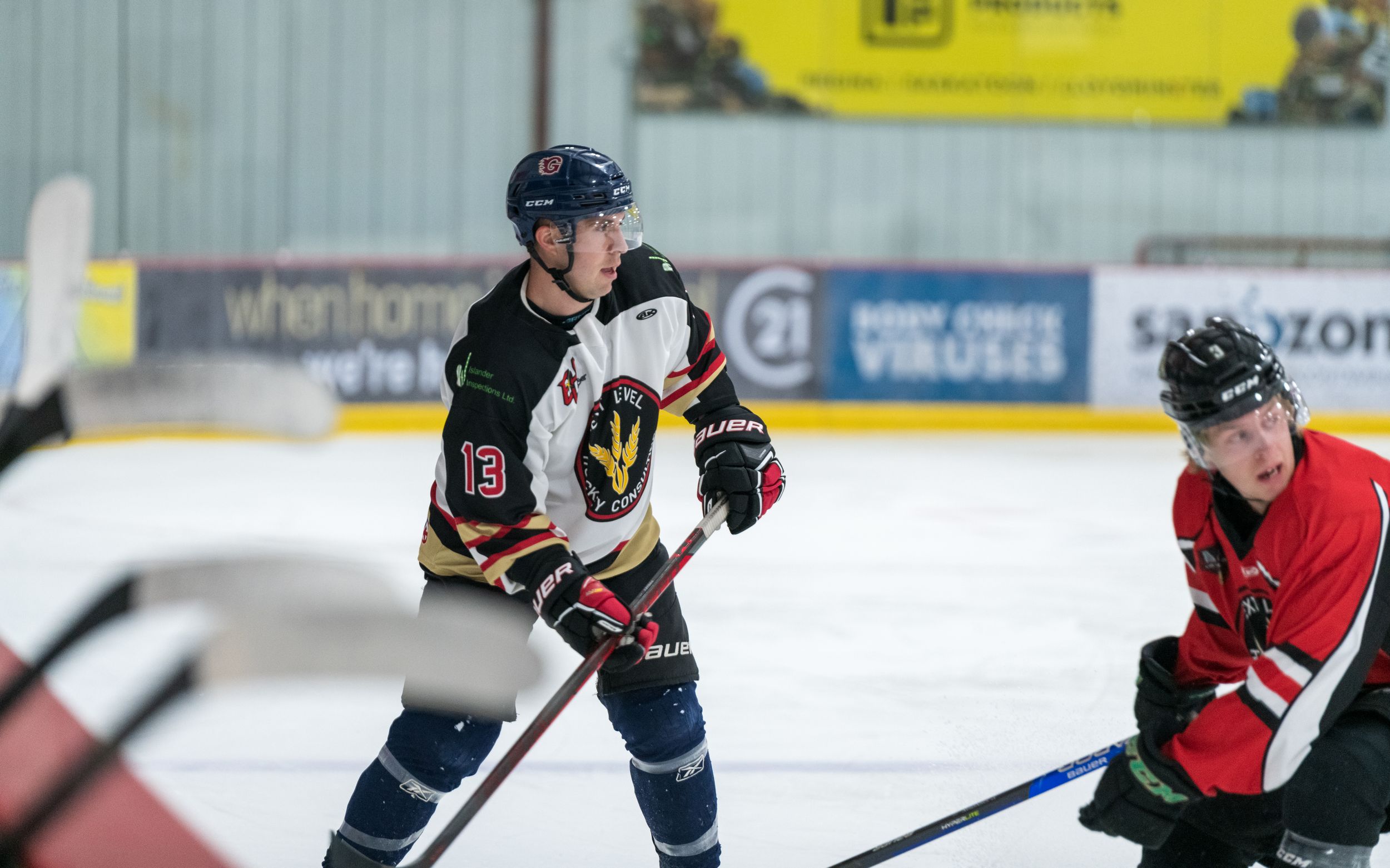 Two hockey players in different colored jerseys compete for the puck during an ice hockey match.