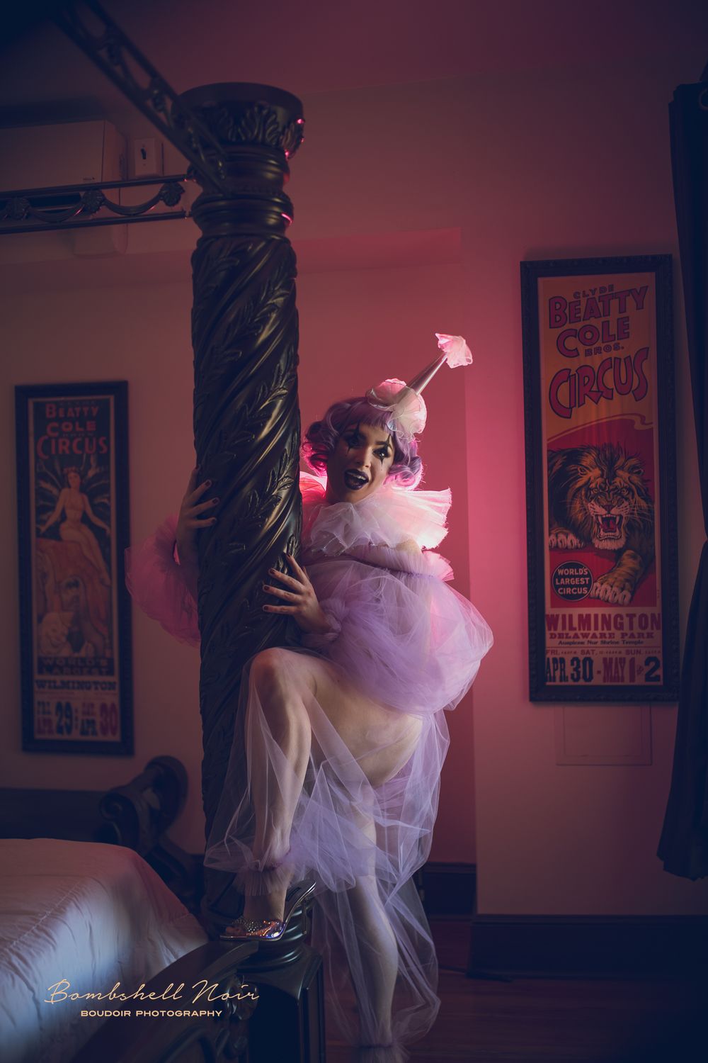 Whimsical scene of someone in a purple tutu and ethereal fabric posing by an ornate pillar with vintage circus posters on the wall.