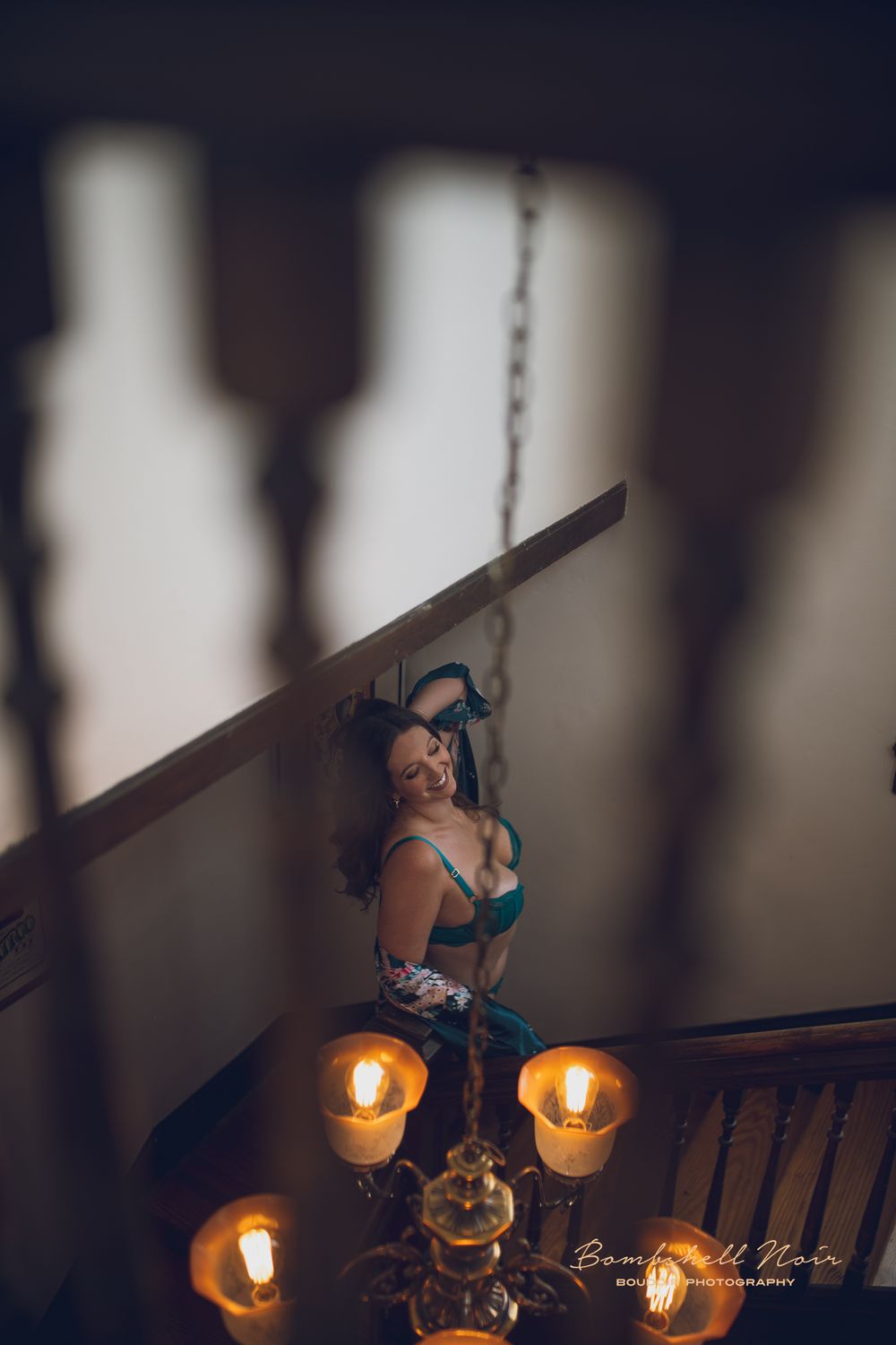 Person poses on a staircase illuminated by warm candlelight, creating a dramatic and moody atmosphere.