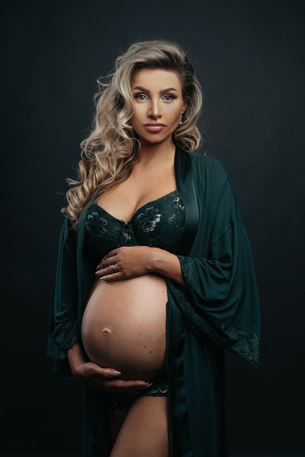 Elegantný tehotenský portrét na tmavom pozadí so smerovým svetlom