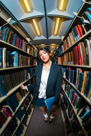 A series of wide-angle shots showing a business person in library stacks under fluorescent lighting.