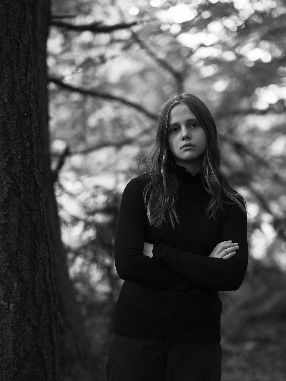 Striking black and white portrait against forest backdrop with soft lighting.