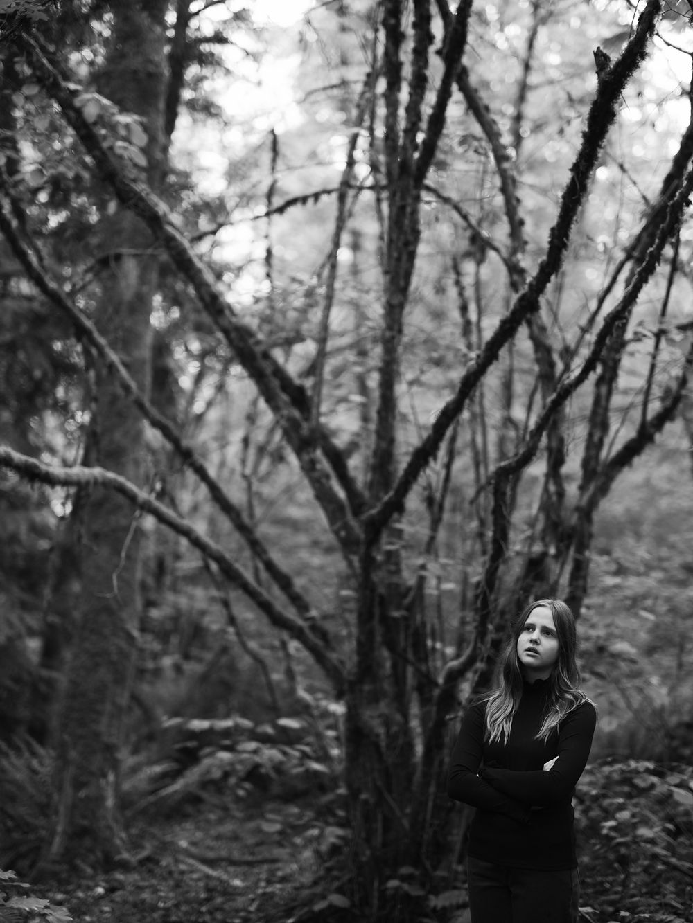Artistic black and white forest portrait with natural branch framing.