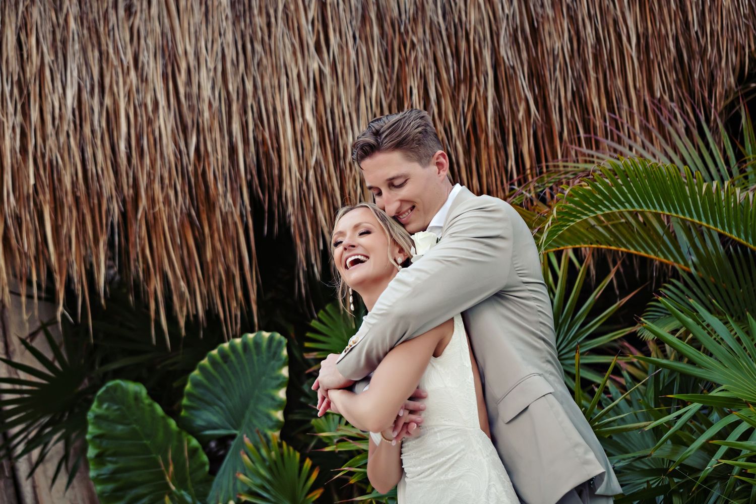 An embrace captured against a rustic backdrop with tropical plants.