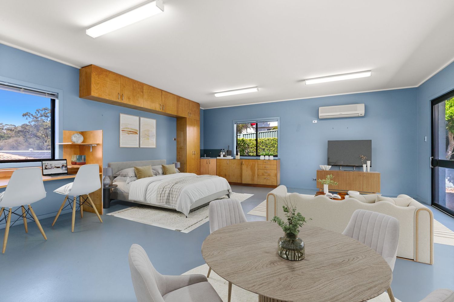Studio-style room with blue walls, timber cabinetry, dining area, bed, and split-system air conditioning.