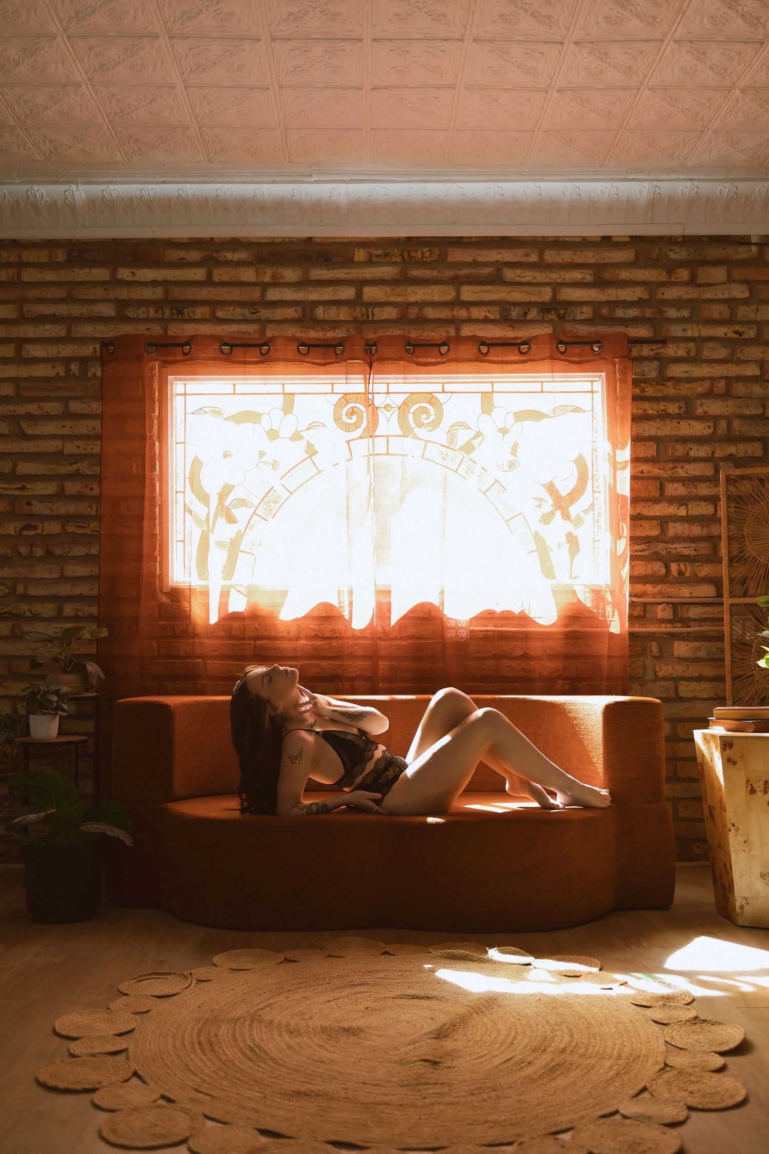 Artistic boudoir photo series showing a person in moody lighting against exposed brick wall with soft window light.