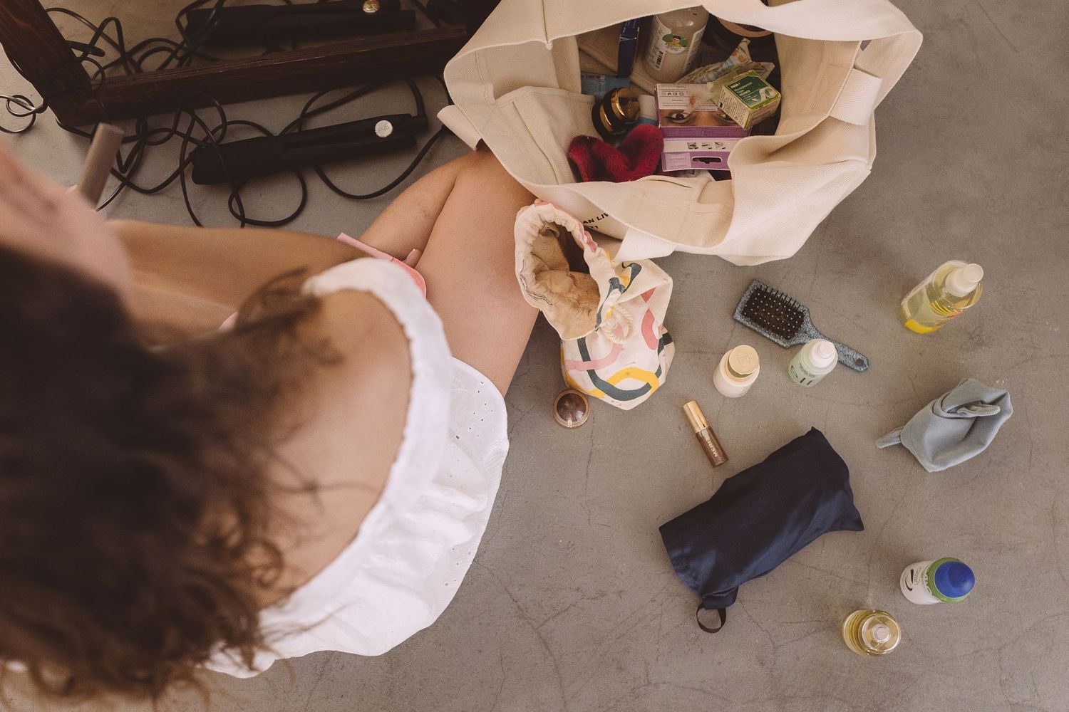 Arial view of beauty products scattered across the floor with a destination bride getting ready for her Santorini wedding.