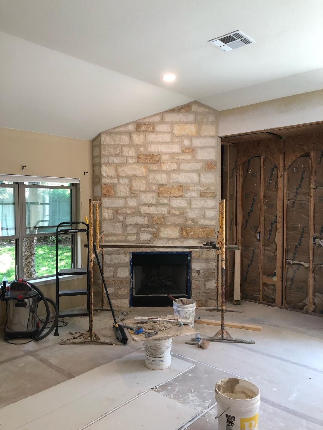 Interior renovation progress showing stone fireplace and exposed walls during home remodeling project.