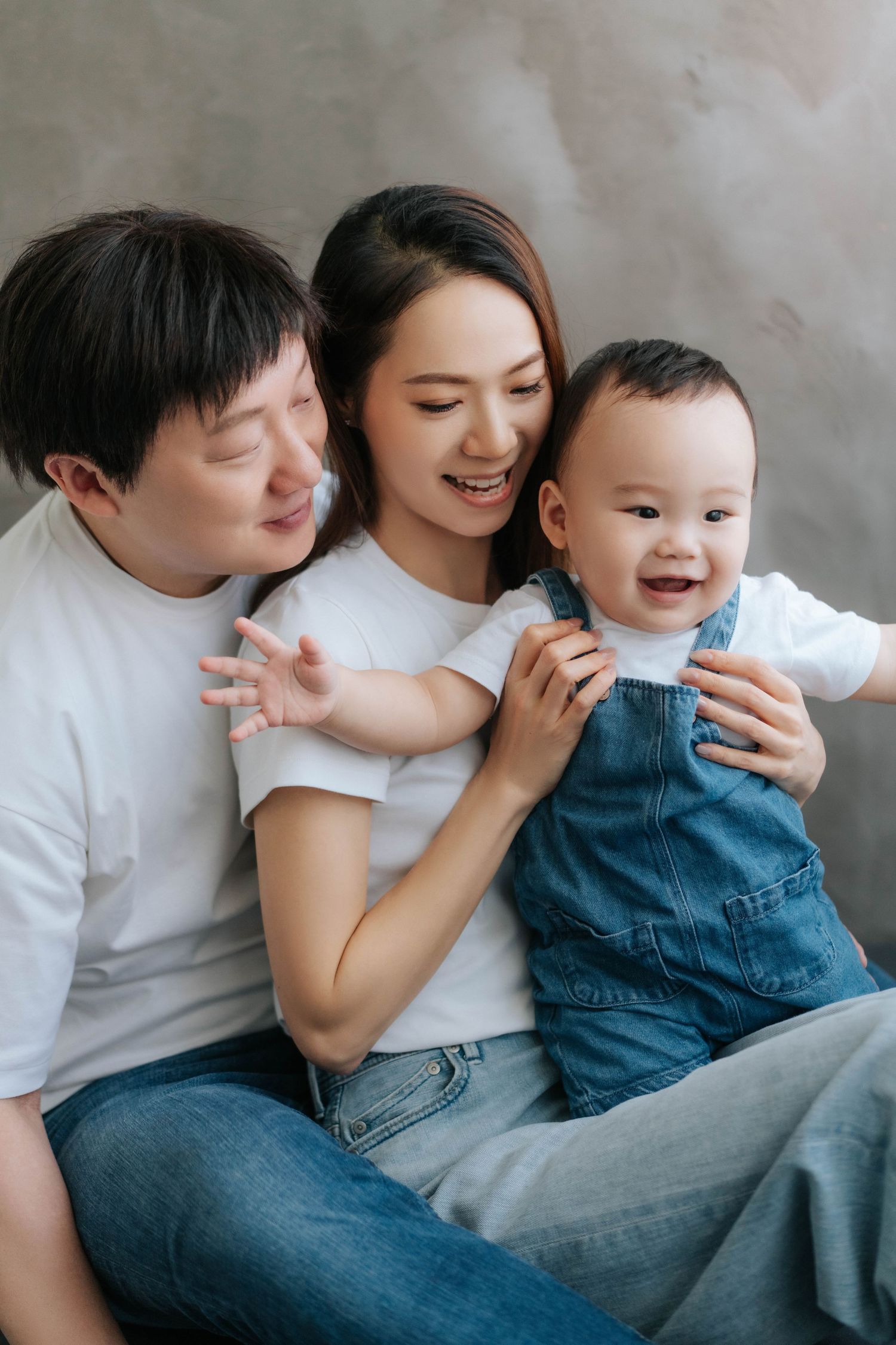 Family in white and denim share tender moments while relaxing together on a couch.一家人穿著白色和牛仔服，在沙發上放鬆地享受溫馨的時刻。