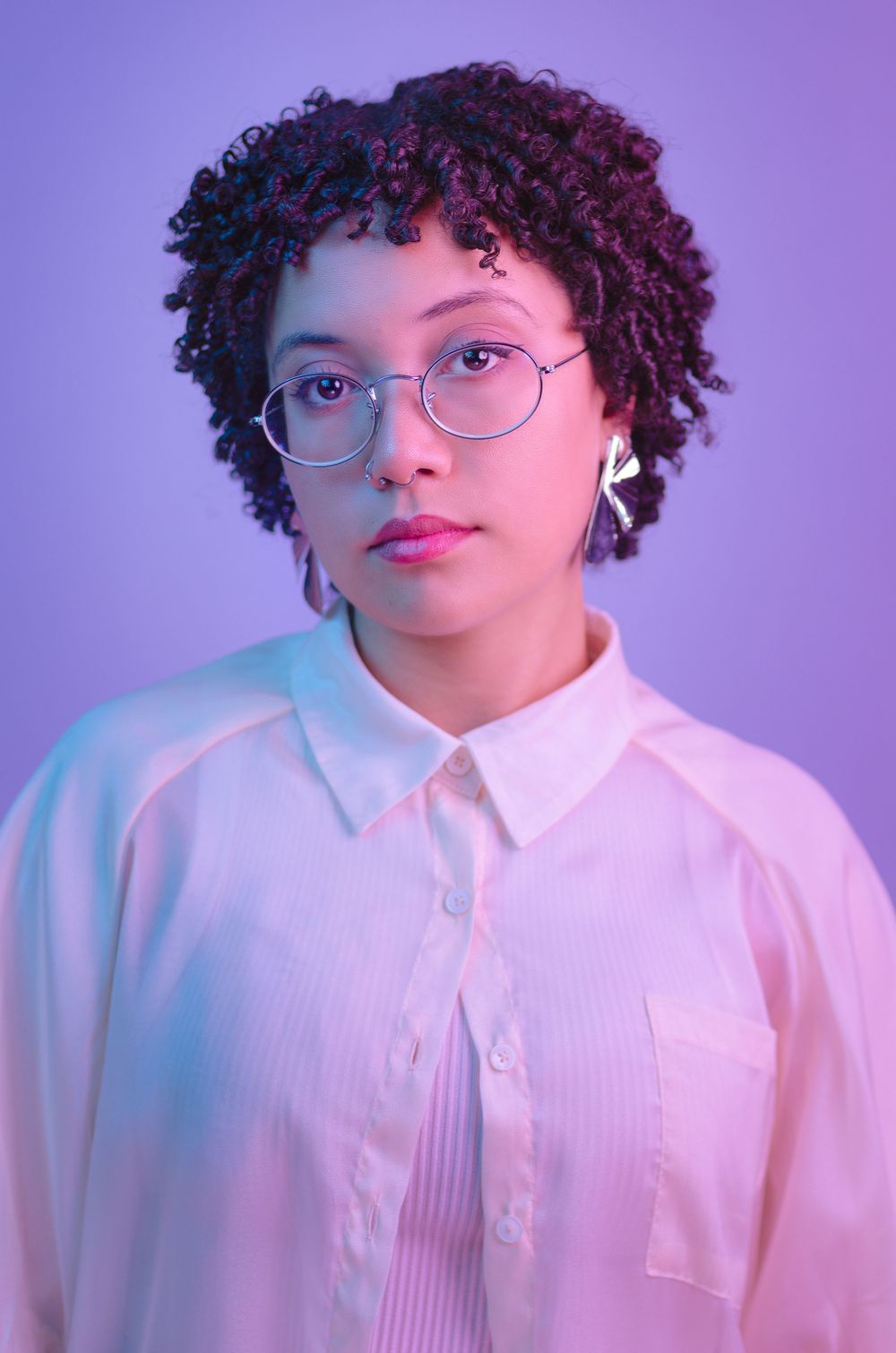 Retrato feminino artístico com iluminação gel rosa e azul. Mulher de óculos em estúdio na Tijuca. Fotografia criativa e moderna no Rio.