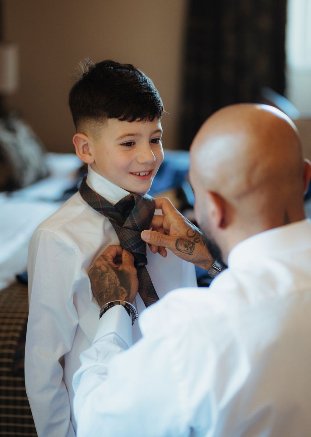 A sequence showing someone in a white dress shirt having their bowtie adjusted in a formal setting.