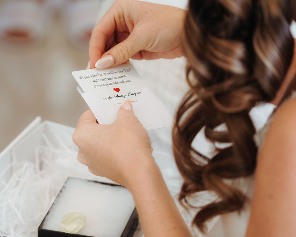 Close-up of hands holding and writing on a small paper note with elegant cursive handwriting.