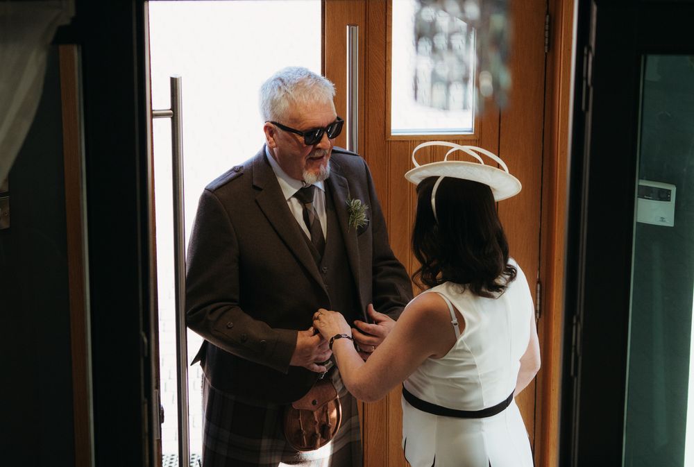 A couple exchanges rings during an intimate indoor wedding ceremony with their dog present.