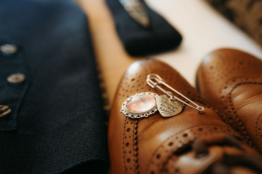 Close-up detail of brown leather Oxford dress shoes showing classic brogue perforations and stitching details.