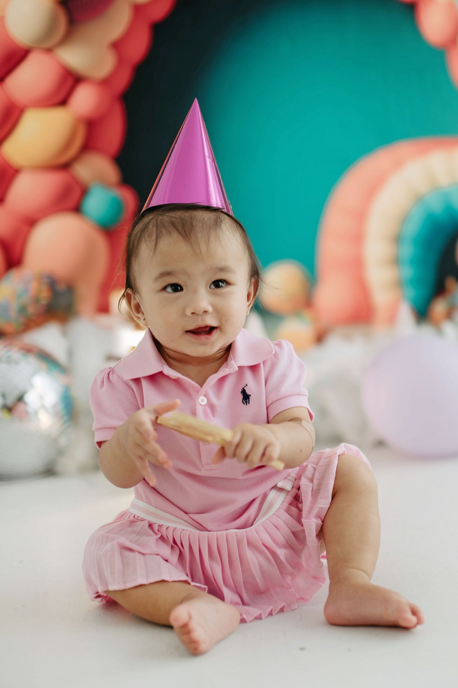 Festive birthday scene with balloon arch decorations against a vibrant teal backdrop.