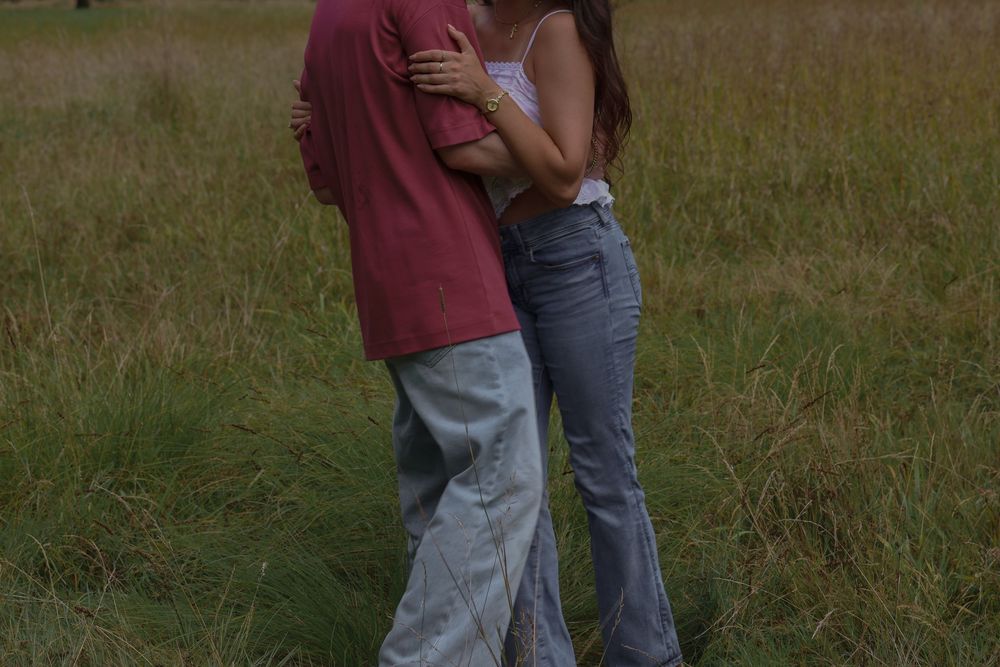 Man and woman embracing each other in grassy field