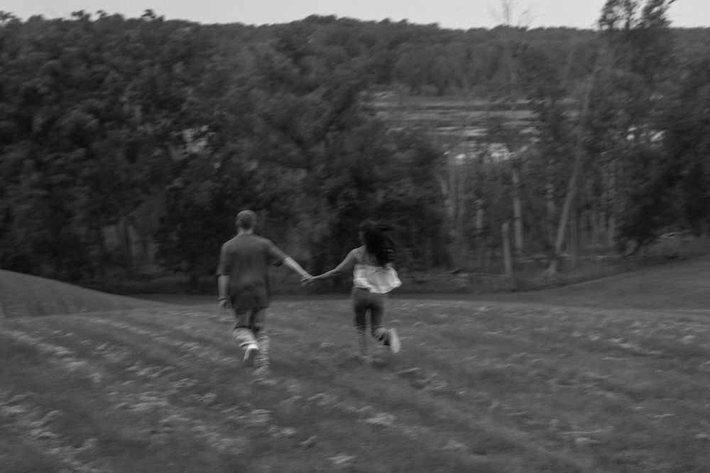 Man and woman holding hands and running away in field