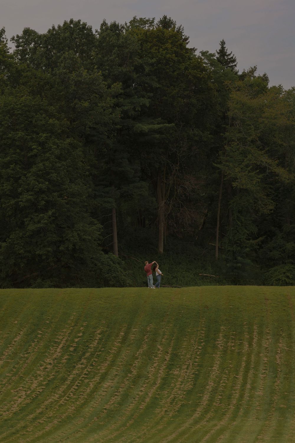 Man and woman off in the distance dancing on a hill top