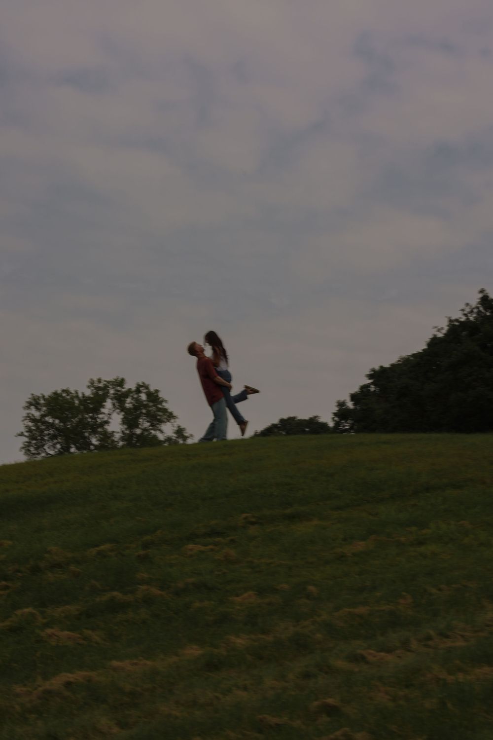 Man holding woman on top of a hill