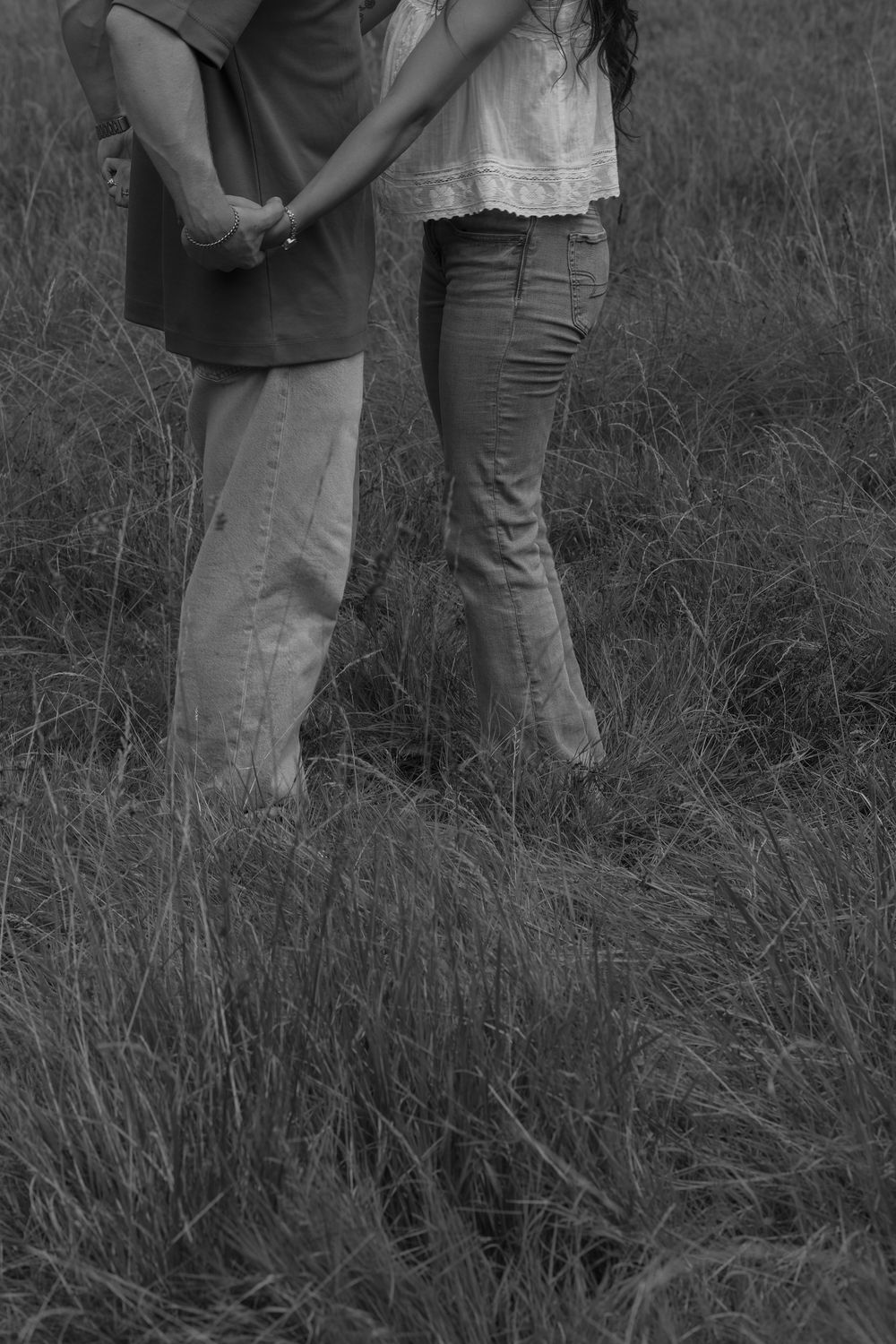 Cropped image of lower half of man and woman holding hands in a grassy field
