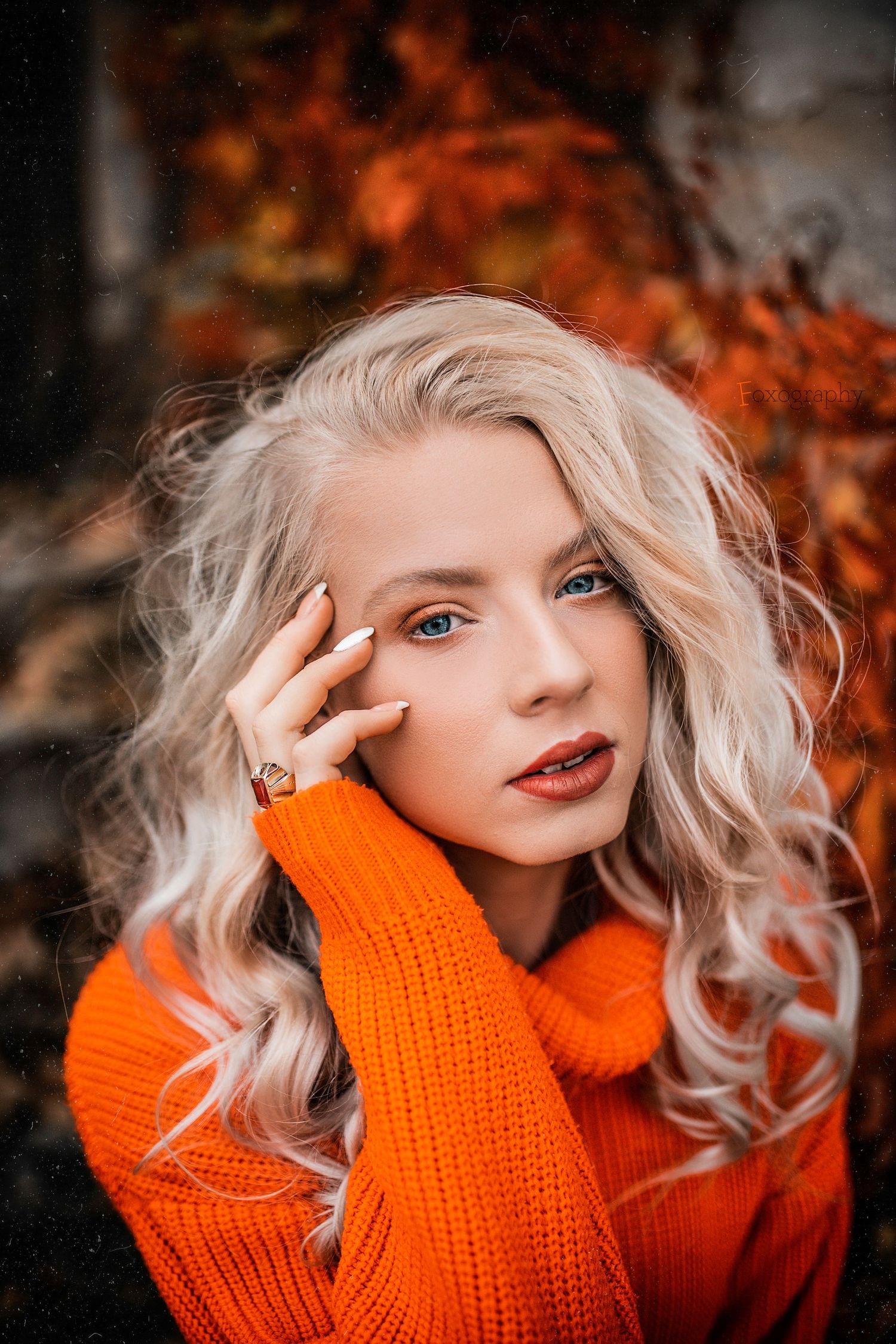 Blondínka v oranžovom roláku pózuje na pozadí pestrofarebného jesenného lístia. Jesenné fotenie, región Žilina.