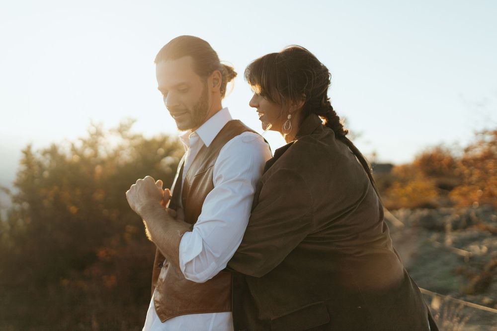 A couple embraces during golden hour in an outdoor setting with warm autumn lighting.
