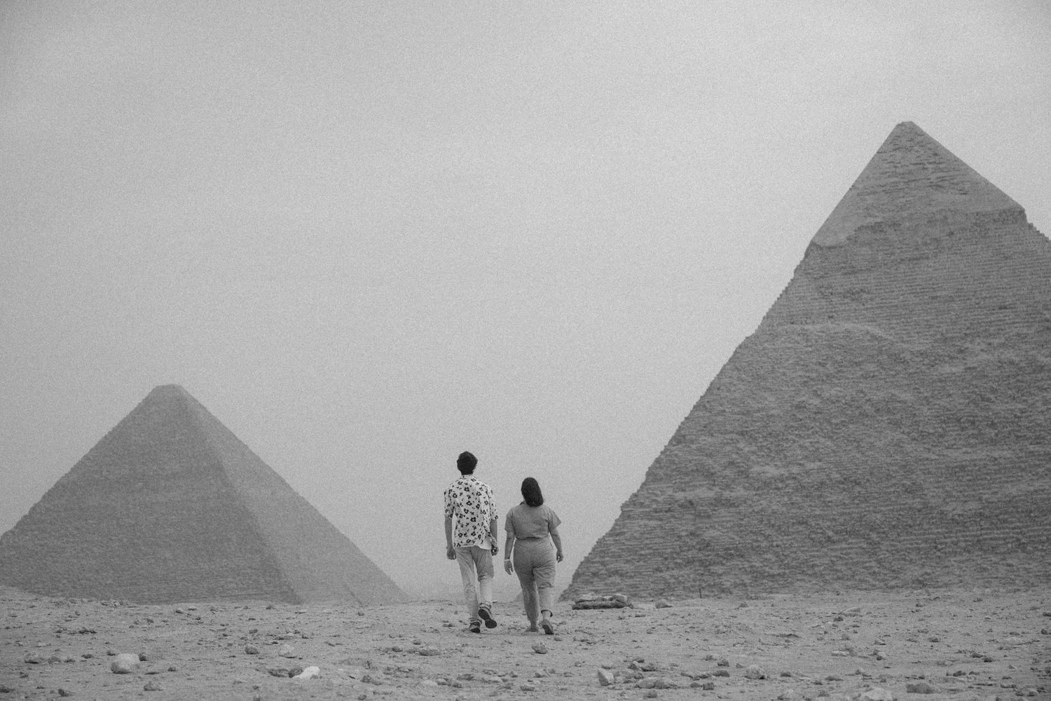 Ancient pyramids of Giza stand majestically in the desert landscape as tourists explore the historic Egyptian site.