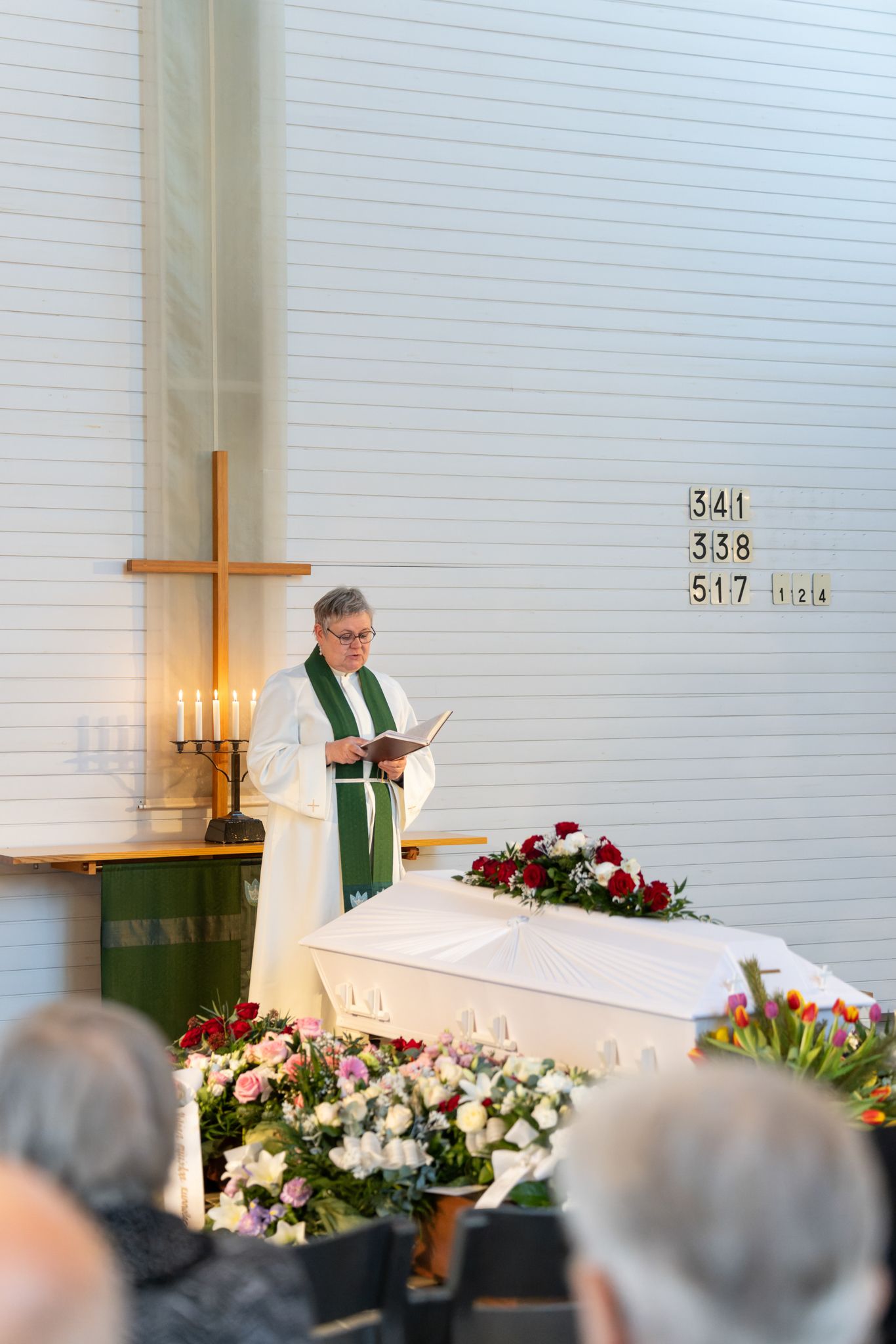 A church altar decorated with white and red floral arrangements and green liturgical banners.