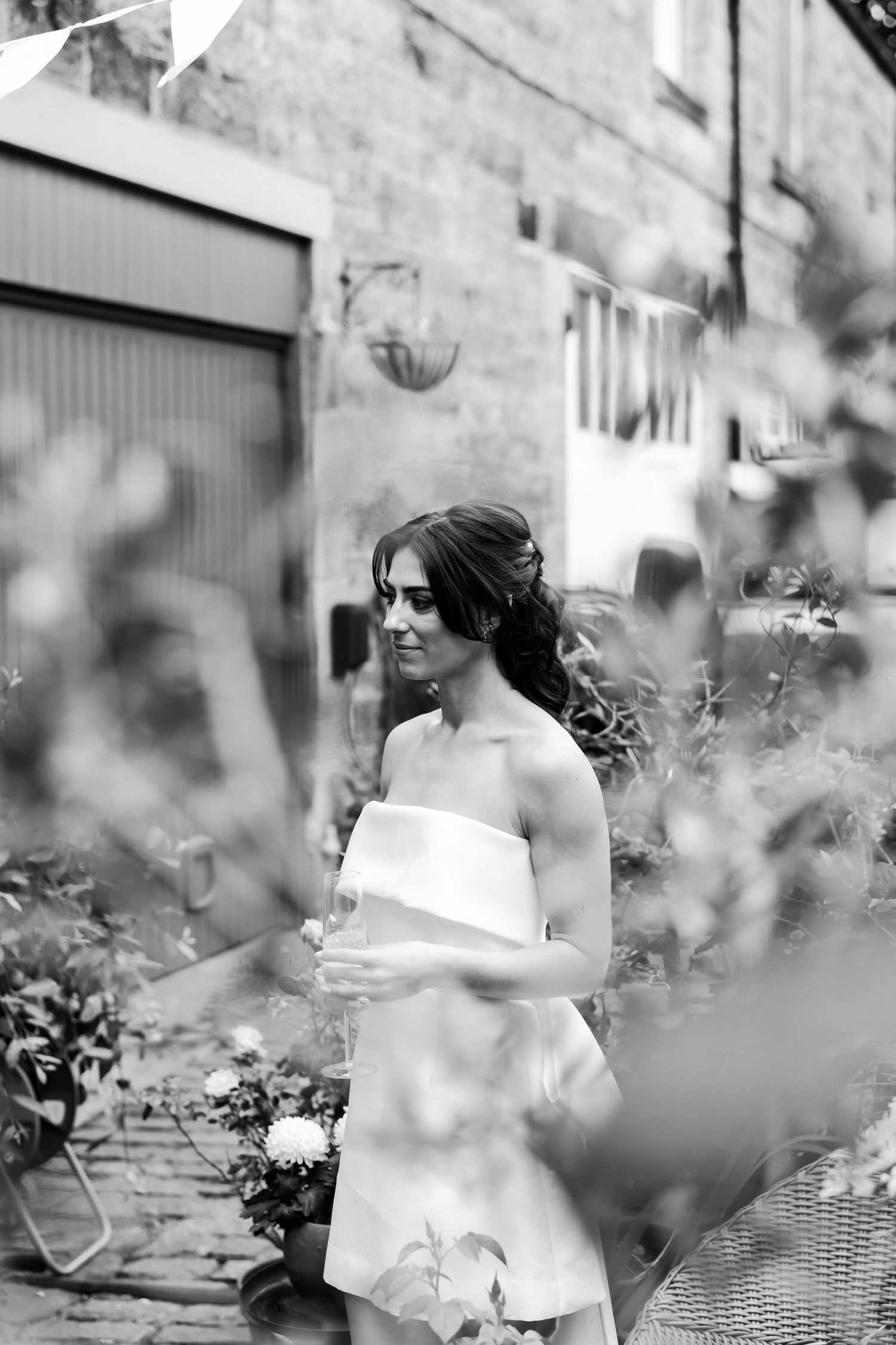 A black and white photo shows a garden scene with flowers and foliage in soft focus creating a dreamy atmosphere.