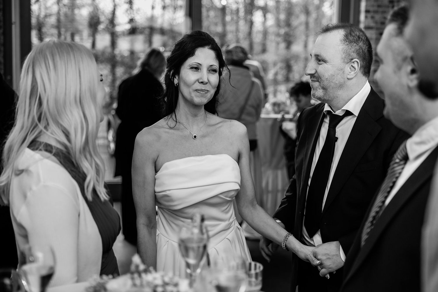 A series of black and white wedding photos showing candid moments between guests during a formal reception celebration.