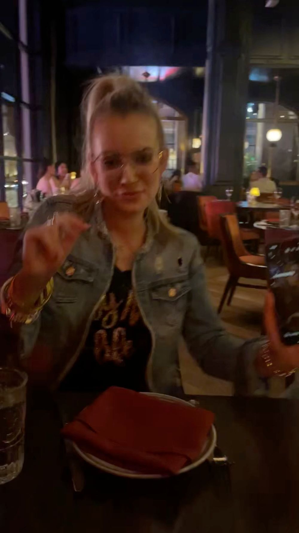 Person in denim jacket dining at a dimly lit restaurant showing sequence of candid expressions and gestures.