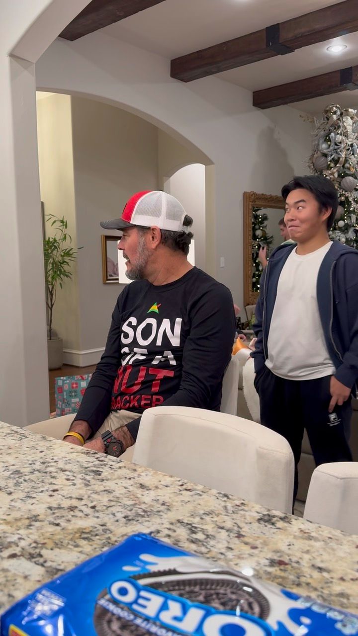 A group of people gathered around a kitchen counter with snacks and Oreo cookies visible on the surface.