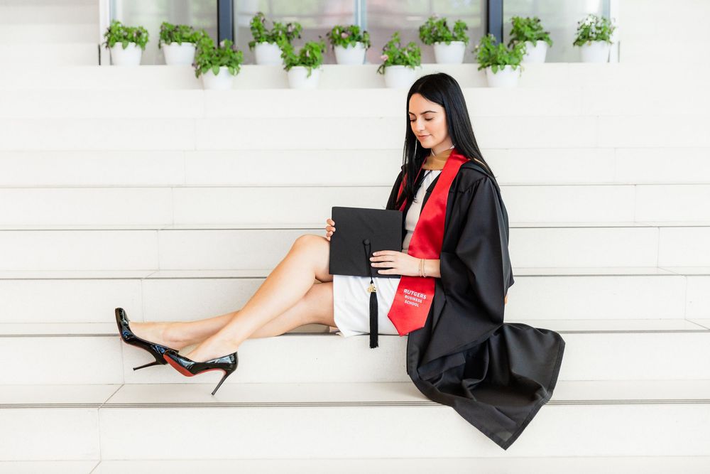 Professional woman in business attire sits on white steps with potted plants above.