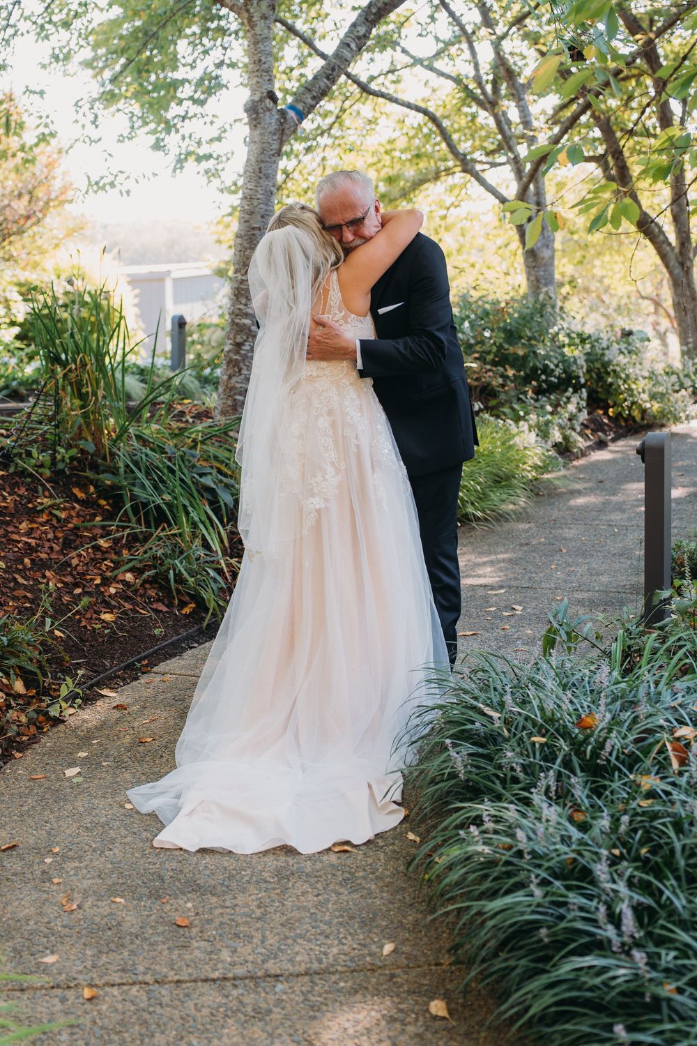 A romantic wedding moment captured in a garden setting with lush greenery and autumn foliage.