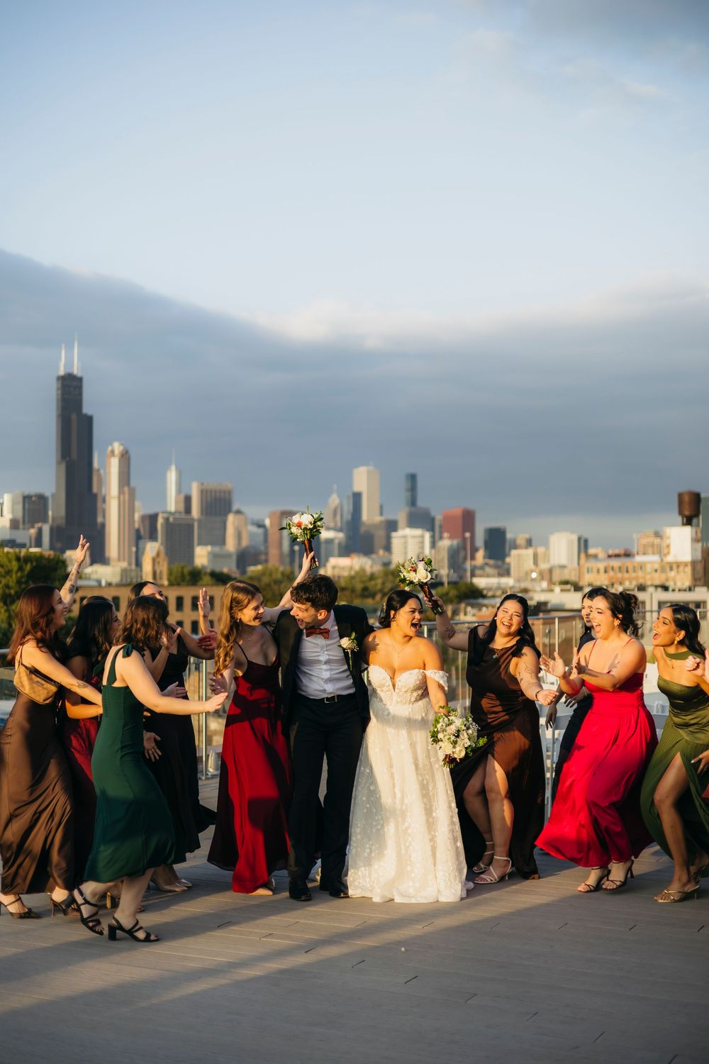 Wedding party dances together on a rooftop with Chicago's iconic skyline in the background at sunset.