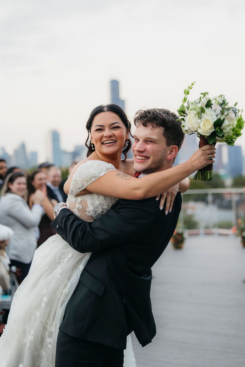 Newlyweds share a joyful moment on a rooftop venue with city skyline in the background right after the ceremony
