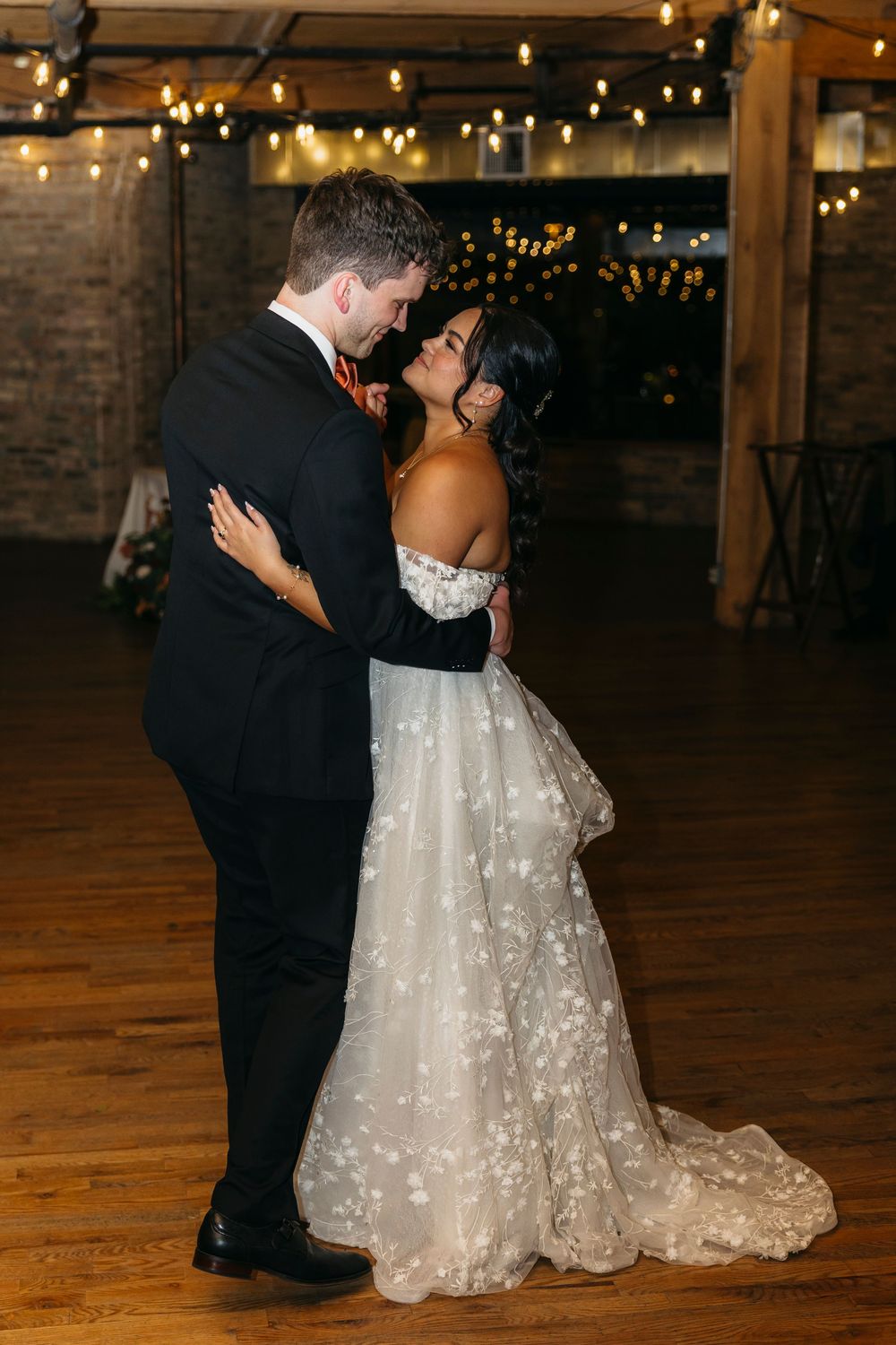 A romantic first dance between newlyweds under twinkling lights at an indoor Chicago wedding reception venue.