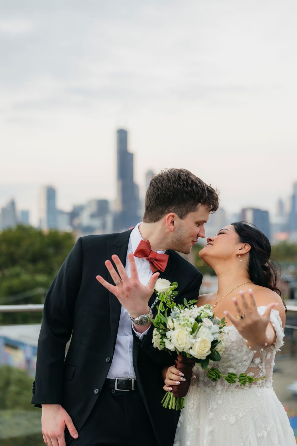 A romantic wedding couple shares kisses against the Chicago skyline backdrop