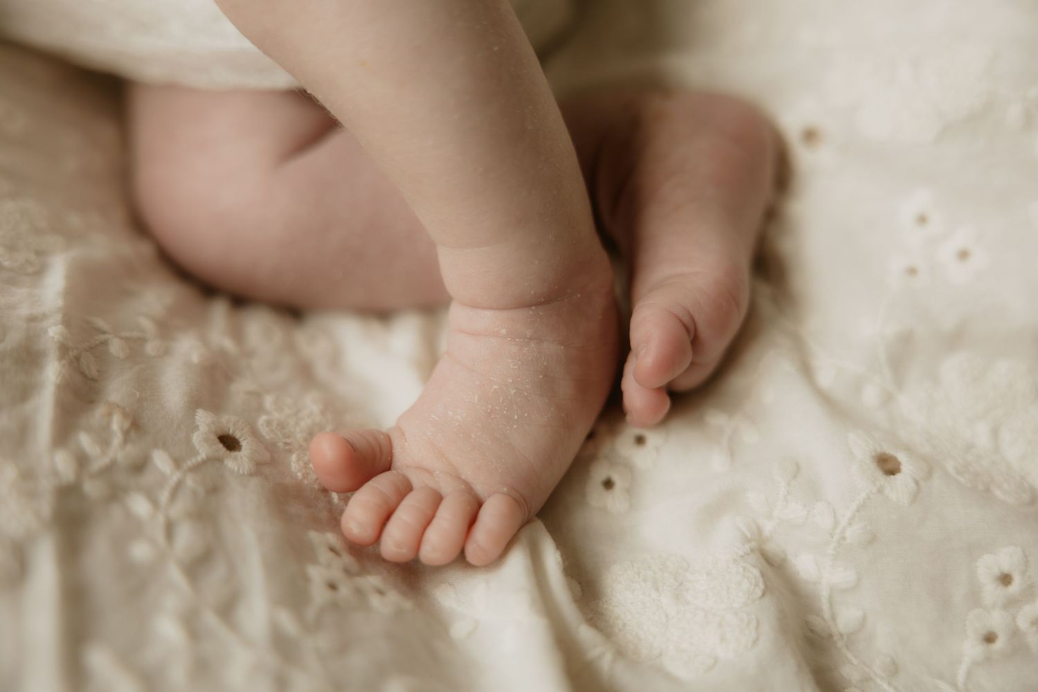 Close-up photos of hands holding and comforting a baby's tiny feet in soft, warm lighting.