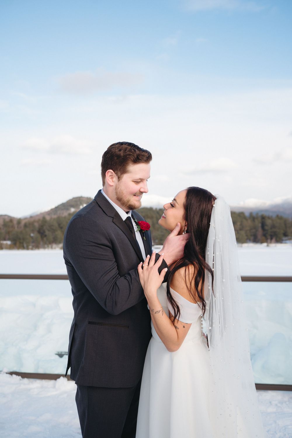 A romantic winter wedding photo series showing a couple kissing in the snow with mountains in the background.