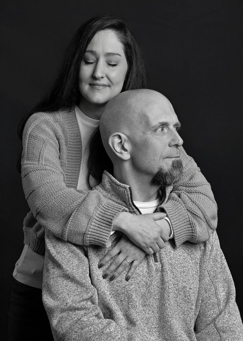 Intimate black and white portrait of a couple embracing in casual sweaters.
