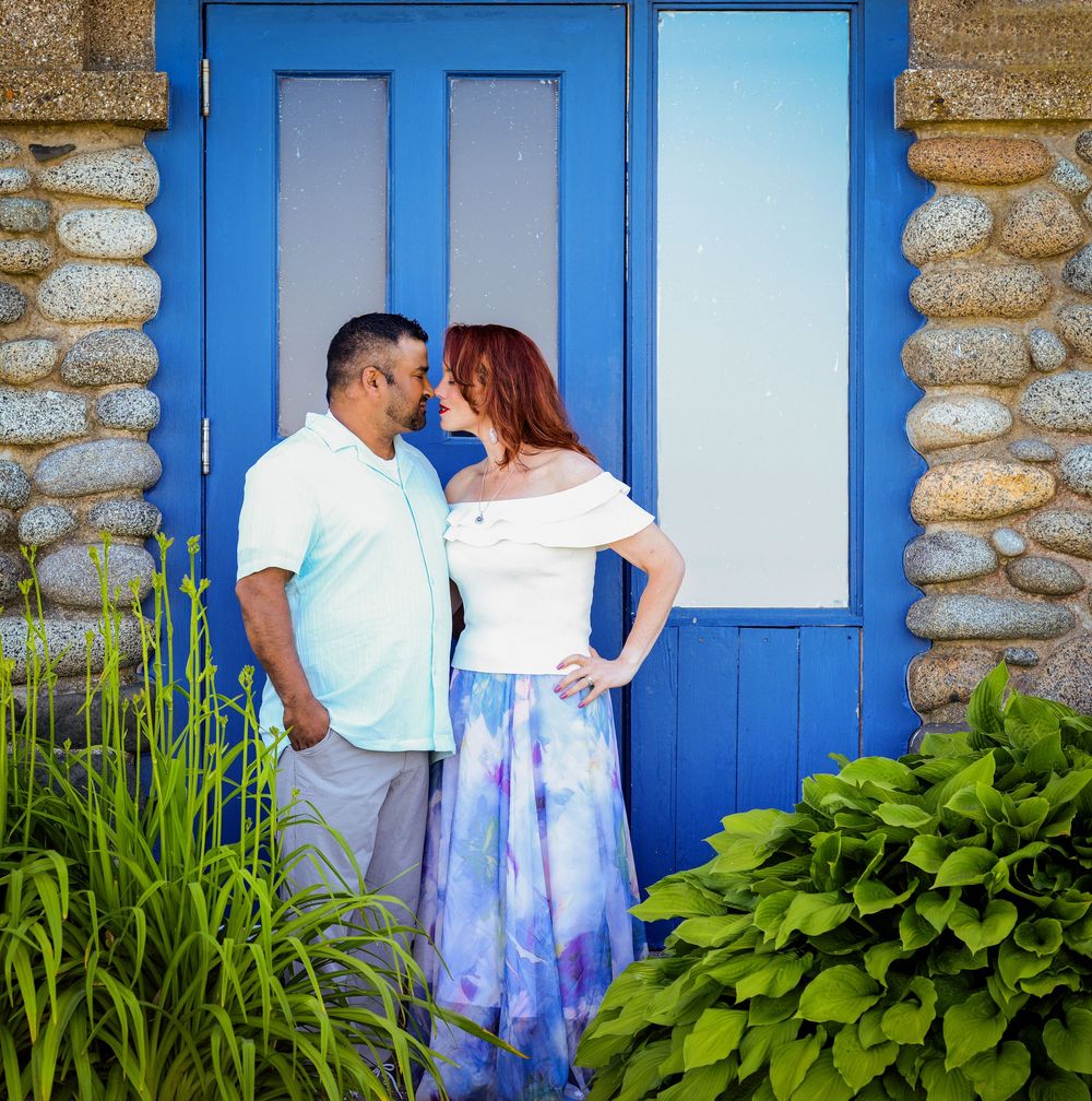 Romantic couple portrait in front of a bright blue door and stone wall.